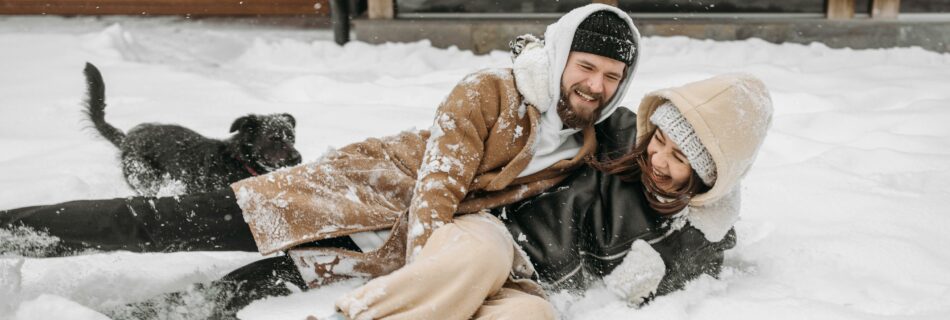 Couple s’amusant dans la neige devant un chalet lors d’un week-end romantique en location dans les Alpes