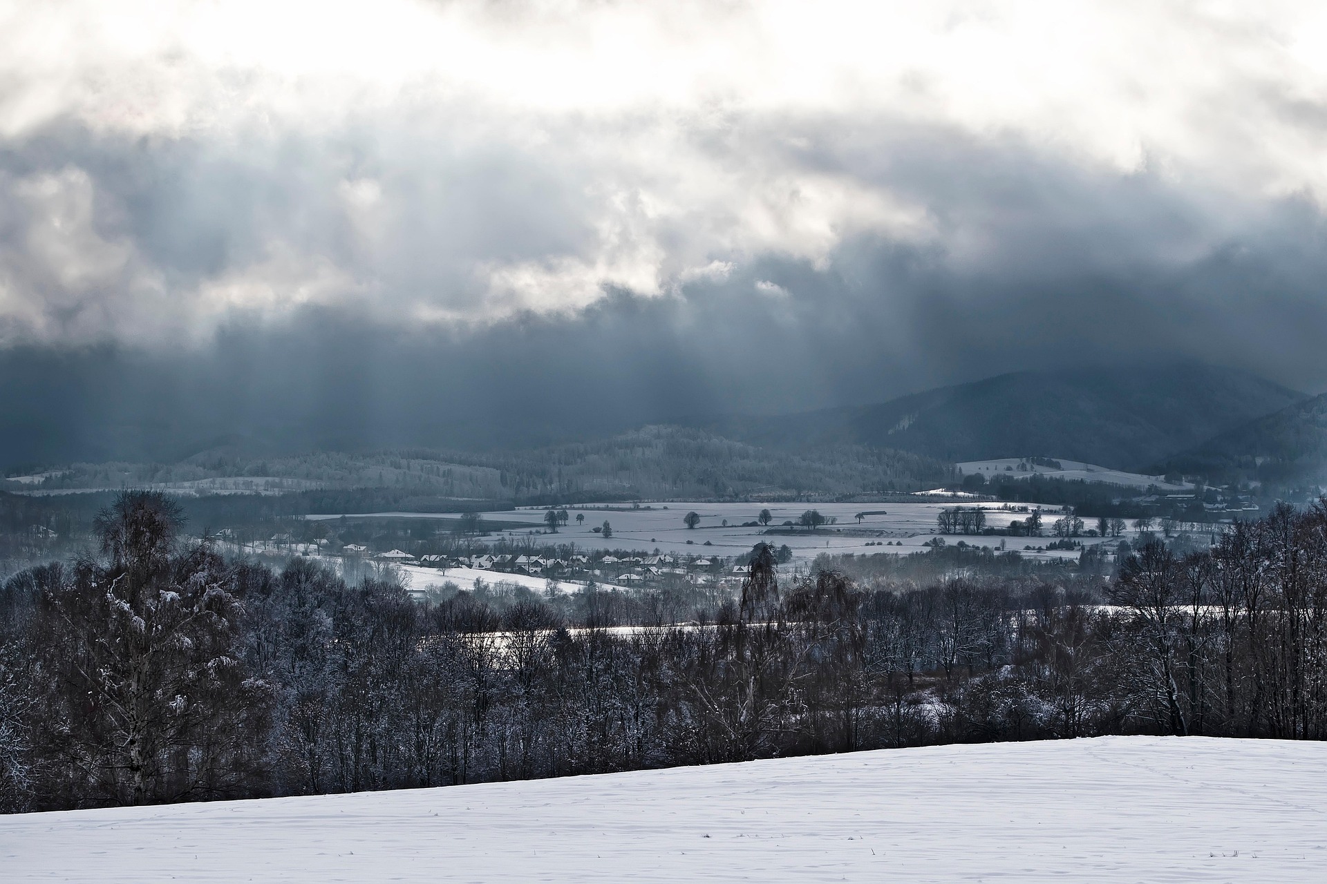Paysage de vallée enneigée sous un ciel hivernal en montagne